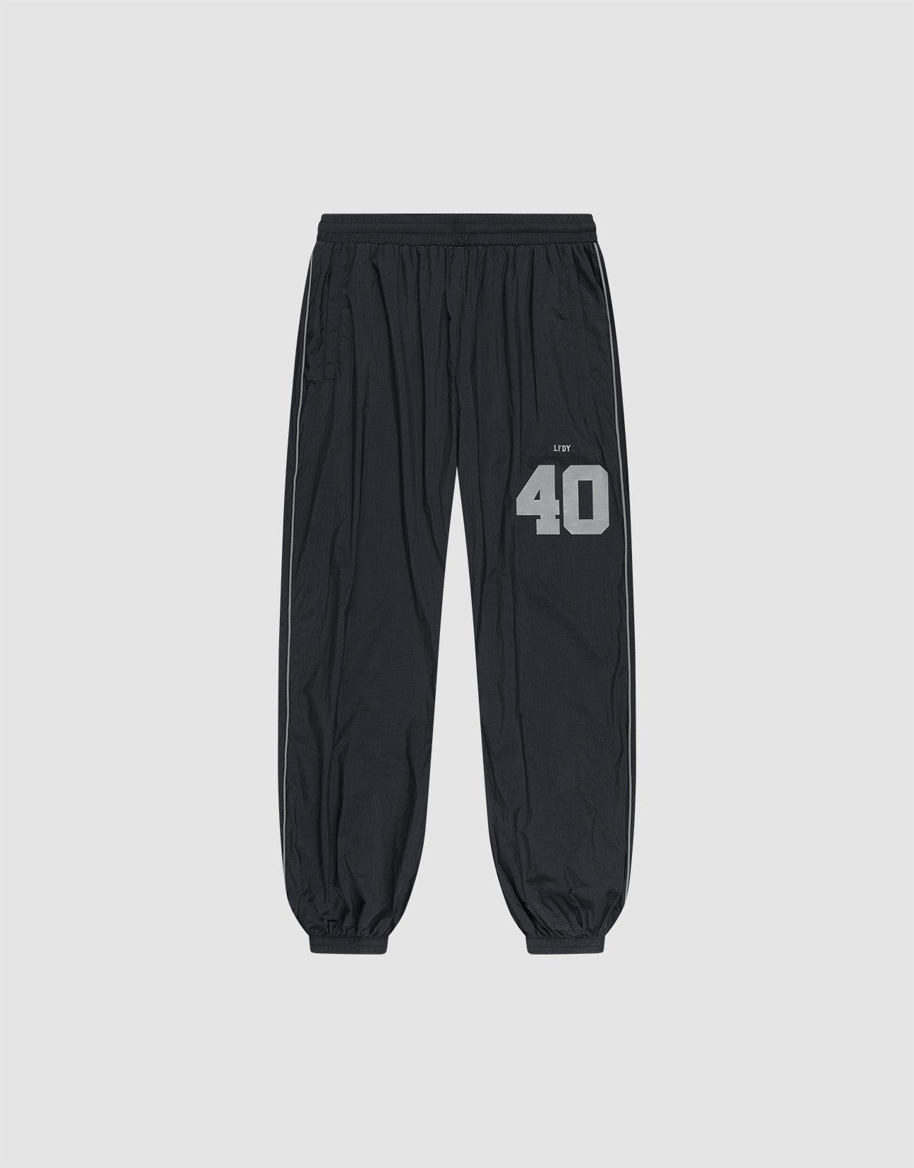 LFDY Performance Trackpants by LIVE FAST DIE YOUNG in black, with elastic waistband and cuffs. Gray reflective "40" and brand print on left thigh, oversize fit. Shown on a plain light gray background.