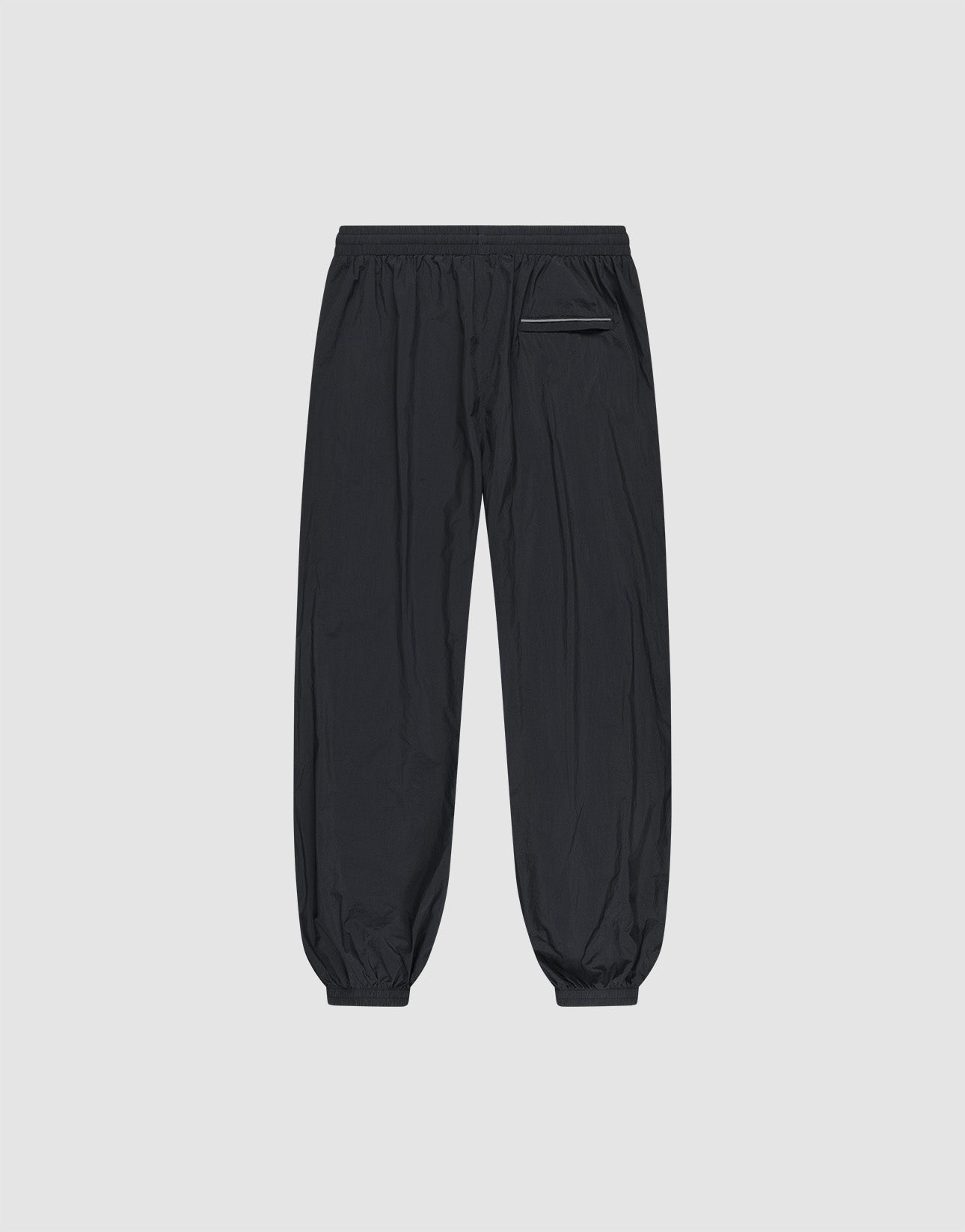 The LFDY Performance Trackpants by LIVE FAST DIE YOUNG feature an oversize fit, 100% nylon fabric, elastic waistband and ankle cuffs, and a single zippered right pocket. Shown flat on a light gray background.