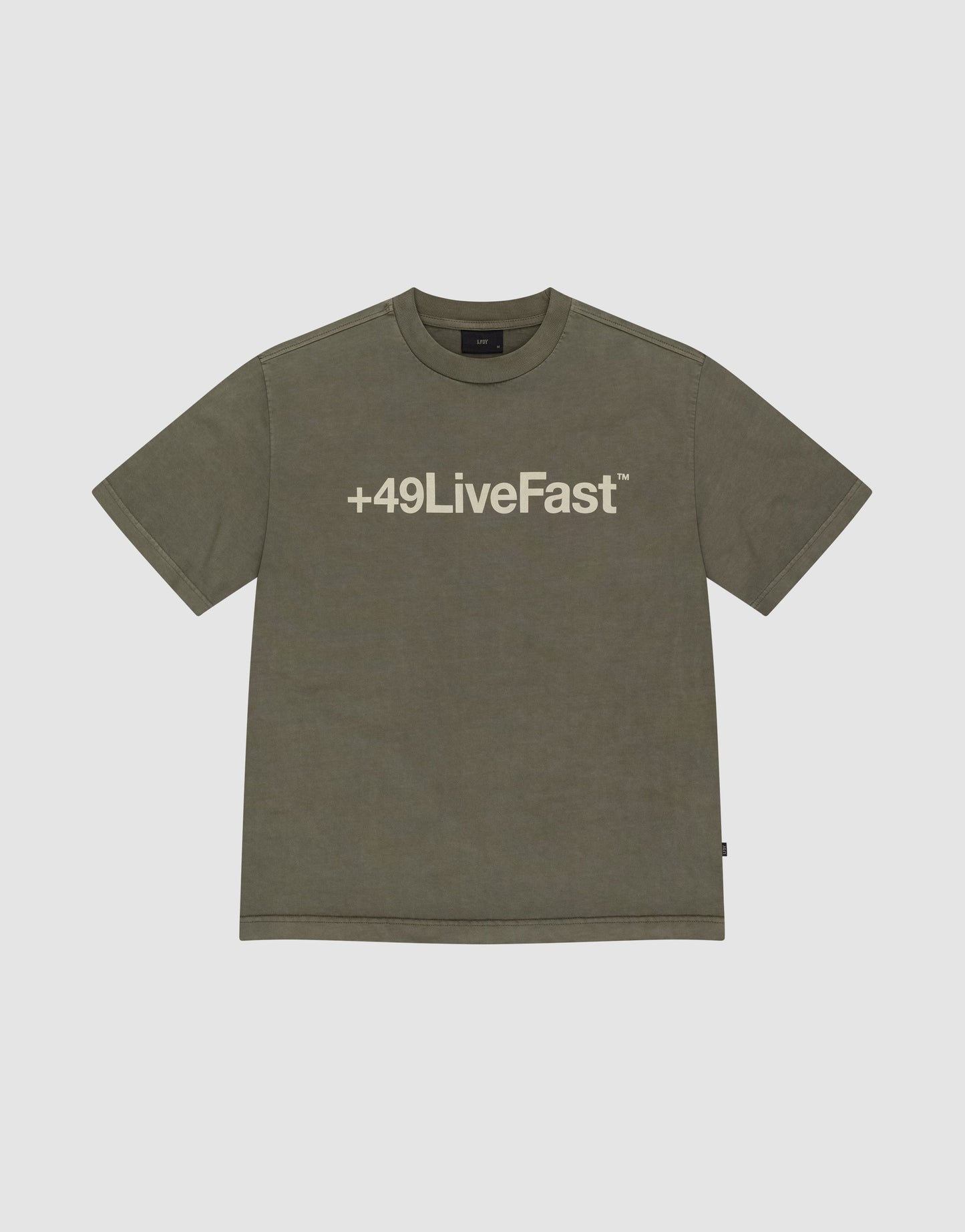 The Basic +49 Tee by LIVE FAST DIE YOUNG is an olive green oversized t-shirt with a bold +49LiveFast™ front print, made from 100% cotton and displayed flat on a light gray background.
