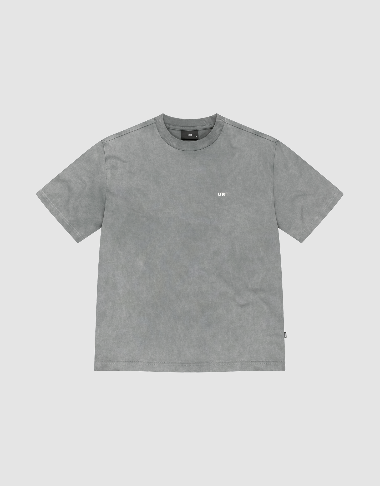 The Basic Trademark Tee by LIVE FAST DIE YOUNG is a gray, short-sleeved crew neck shirt with a small white logo on the upper left chest, made from 100% Baumwolle and displayed flat on a light gray background. | plain