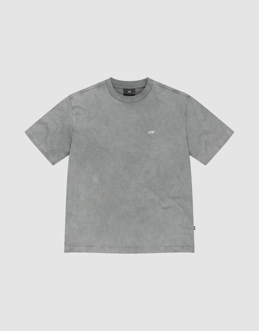 The Basic Trademark Tee by LIVE FAST DIE YOUNG is a gray, short-sleeved crew neck shirt with a small white logo on the upper left chest, made from 100% Baumwolle and displayed flat on a light gray background.