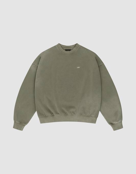 The Basic Chest Sweater by LIVE FAST DIE YOUNG is an olive green, oversized crewneck with long sleeves, ribbed cuffs and hem, a small white LIFT logo on the left chest, and a subtle handgefertigter Fade-Effekt for a unique faded look.
