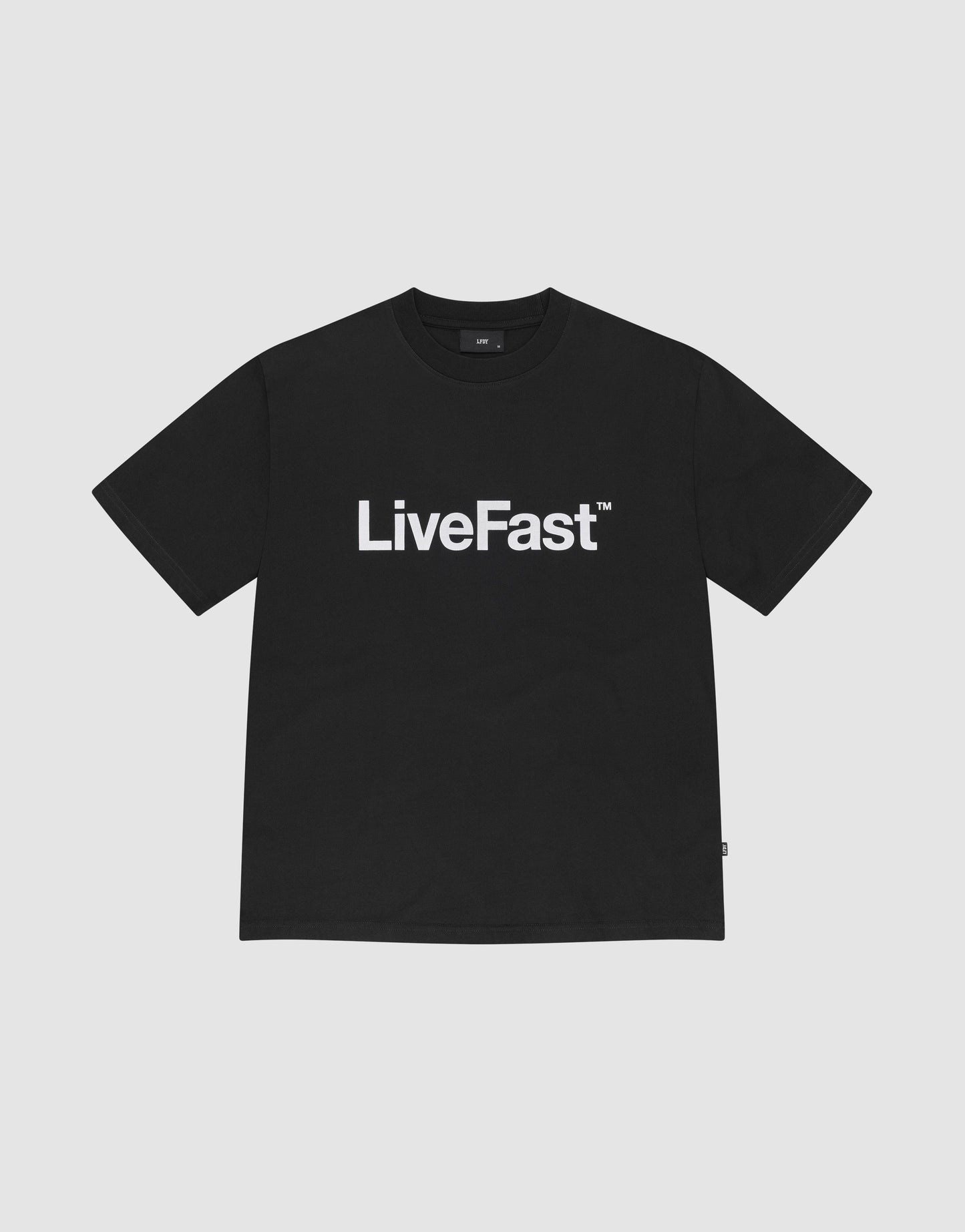 The Basic LiveFast Tee by LIVE FAST DIE YOUNG is a black regular fit T-shirt with a bold "LiveFast™" front print, made from 100% Baumwolle, shown on a plain light gray background.