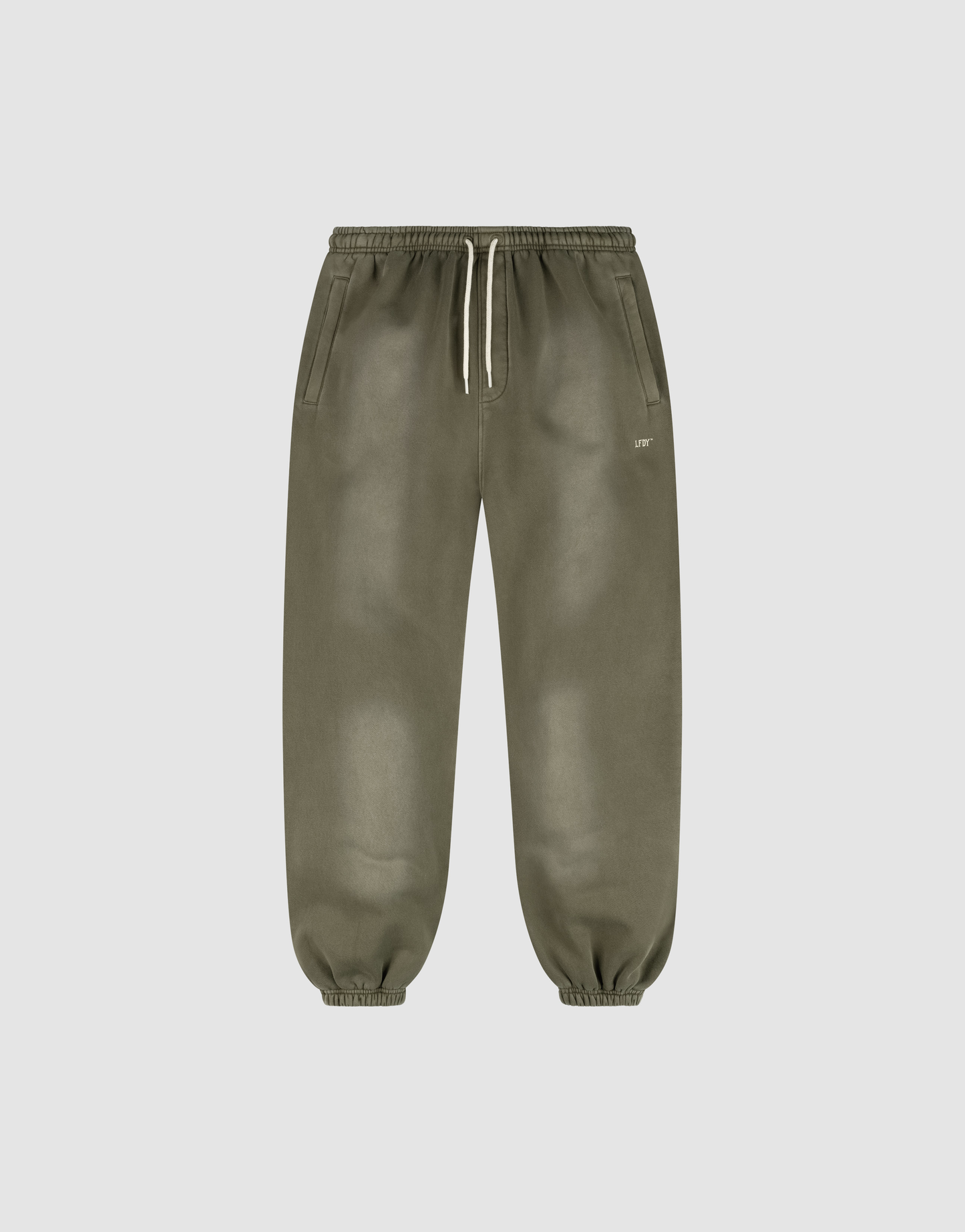 The LIVE FAST DIE YOUNG Basic Loose Jogger features olive green fabric with a handgefertigter Fade-Effekt, an elastic waistband with a white drawstring, side pockets, elastic ankle cuffs, and a small white logo near the left pocket.