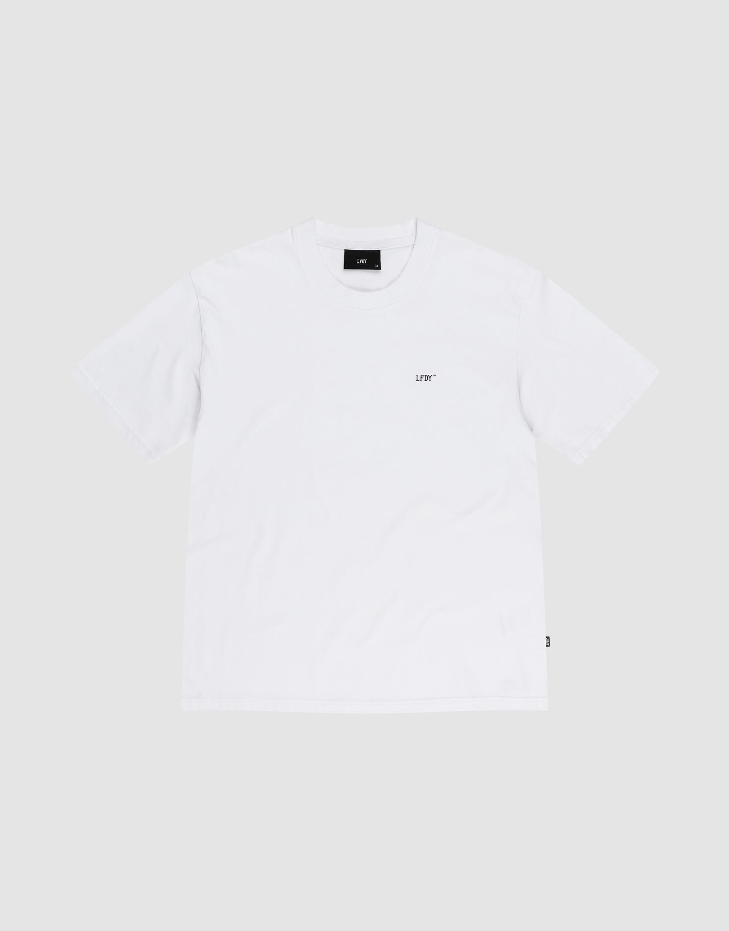 The LIVE FAST DIE YOUNG Basic Chest Tee is a regular fit, short-sleeve white T-shirt made from 100% Baumwolle with a small black UDF logo on the left chest, shown flat on a light gray background.