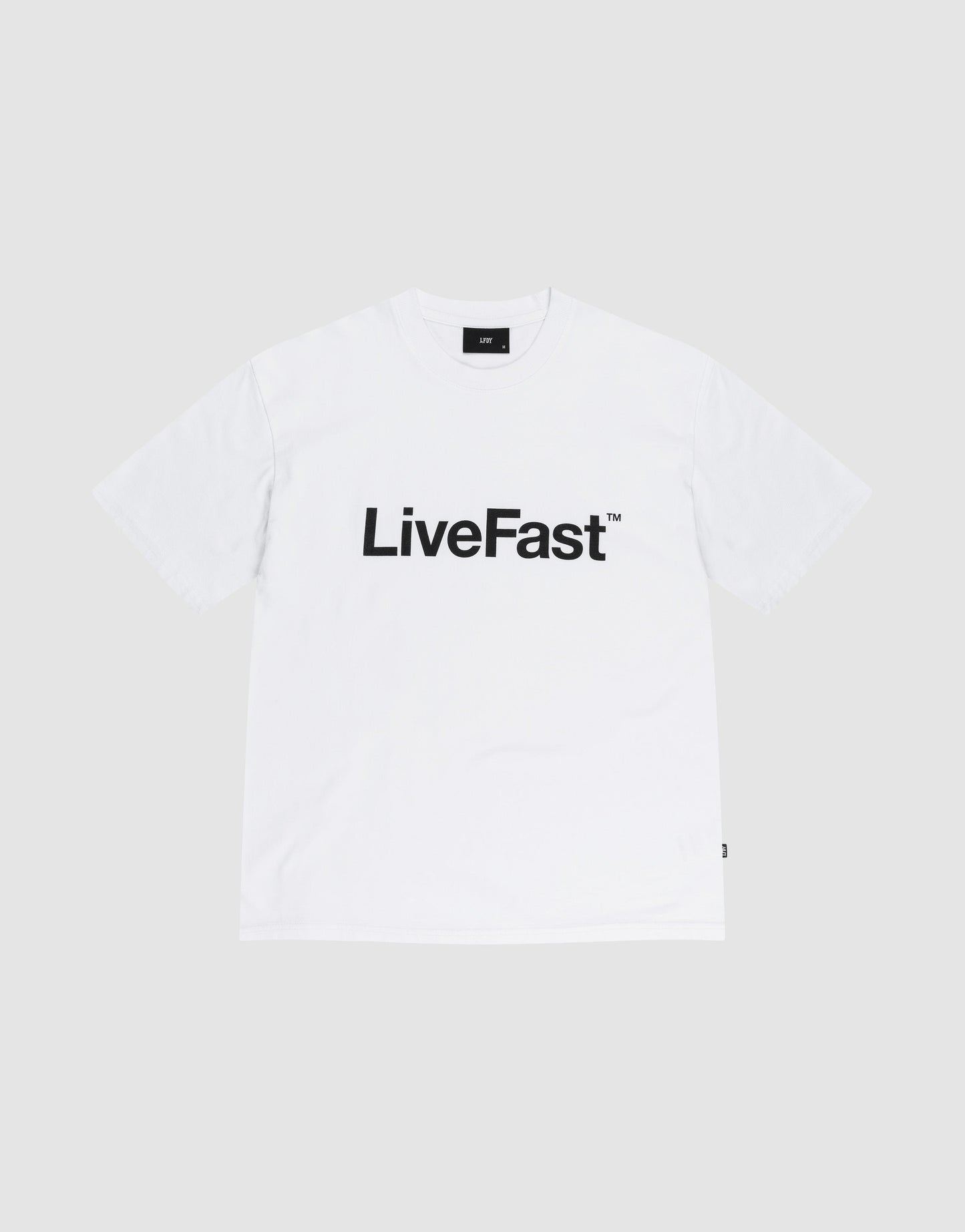 The Basic LiveFast Tee by LIVE FAST DIE YOUNG is a Regular Fit plain white T-shirt featuring a bold black "LiveFast™" front print, laid flat on a light gray background. Crafted from 100% Baumwolle for comfort and style.