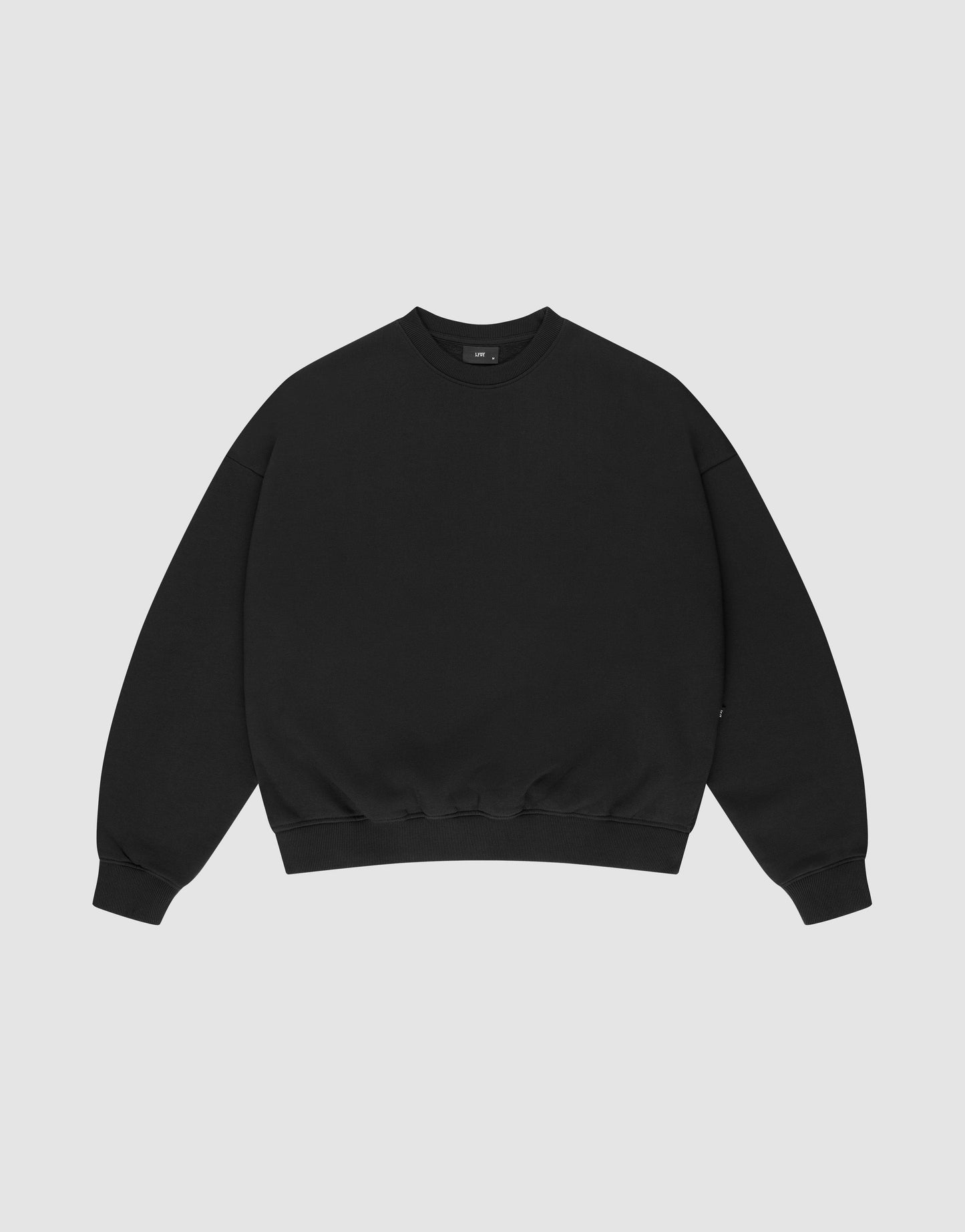 The LIVE FAST DIE YOUNG Basic Blank Sweater is an oversized black crewneck with long sleeves, ribbed cuffs and hem, made from a Baumwolle-Polyester blend, shown on a light gray background.