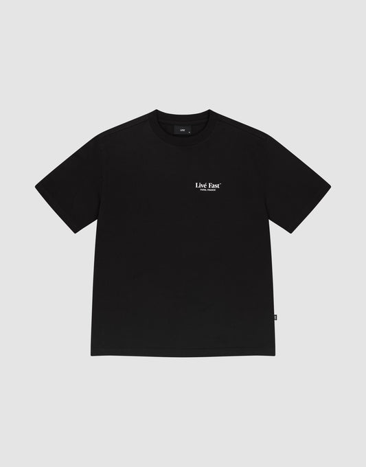 The LFDY Paris Tee by LIVE FAST DIE YOUNG is a black 100% cotton short-sleeve shirt with small white "Live Fast" text on the upper chest, shown on a plain light gray background.