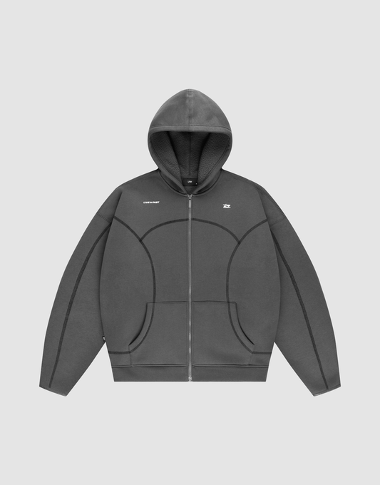 The LFDY Active Fleece Hooded Zip by LIVE FAST DIE YOUNG is a dark gray, oversized zip-up hoodie with a hood, subtle seam details, and a small white logo on the chest, shown against a plain light gray background. | plain