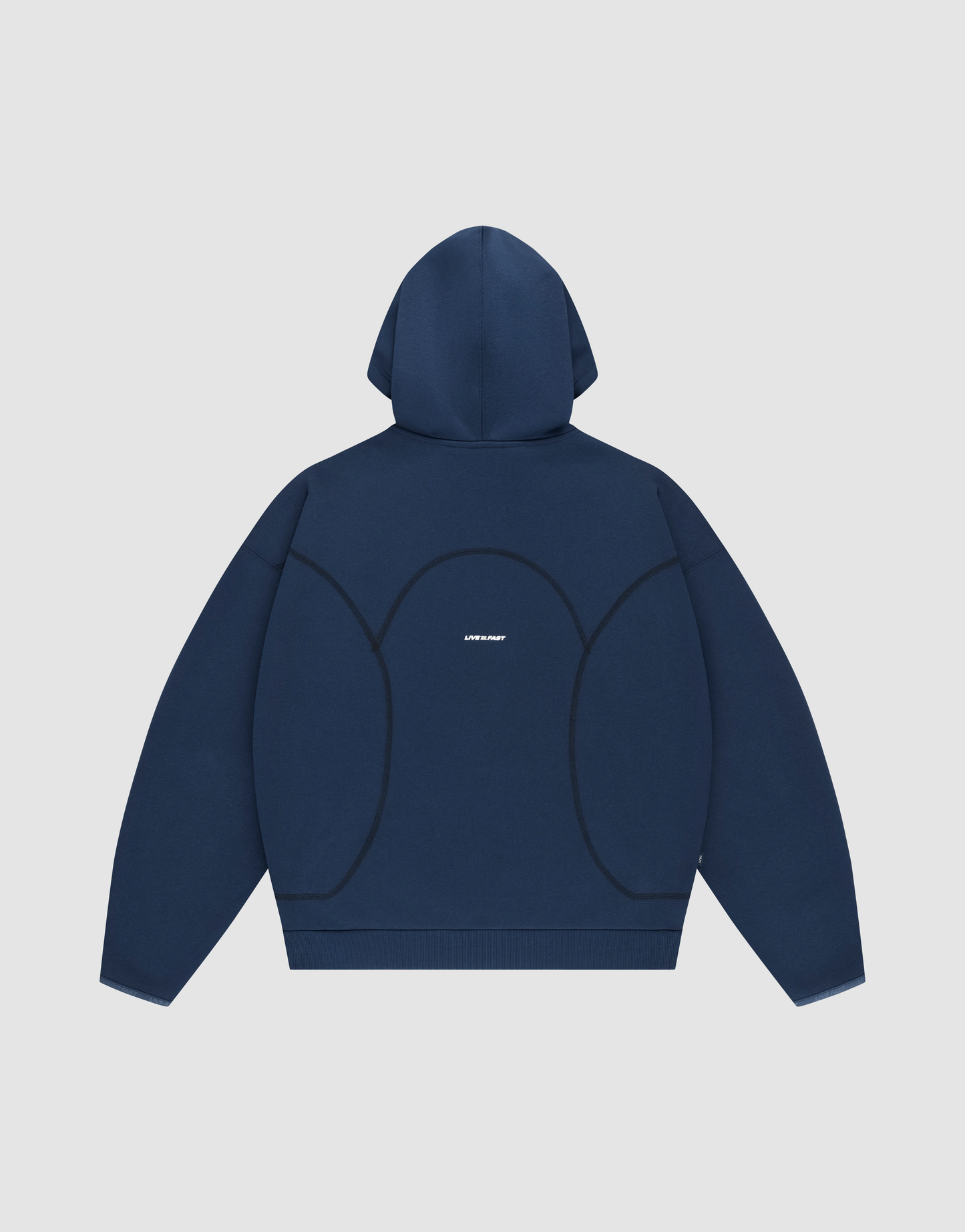 The LFDY Active Fleece Hooded Zip by LIVE FAST DIE YOUNG is shown laid flat, back facing up. This navy blue oversized hoodie features curved black seams, a small white logo at the center, and is set on a light gray background.