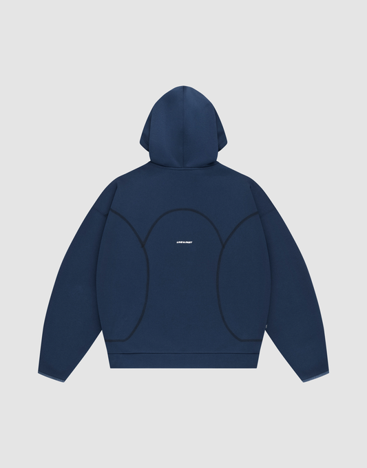 The LFDY Active Fleece Hooded Zip by LIVE FAST DIE YOUNG is shown laid flat, back facing up. This navy blue oversized hoodie features curved black seams, a small white logo at the center, and is set on a light gray background.