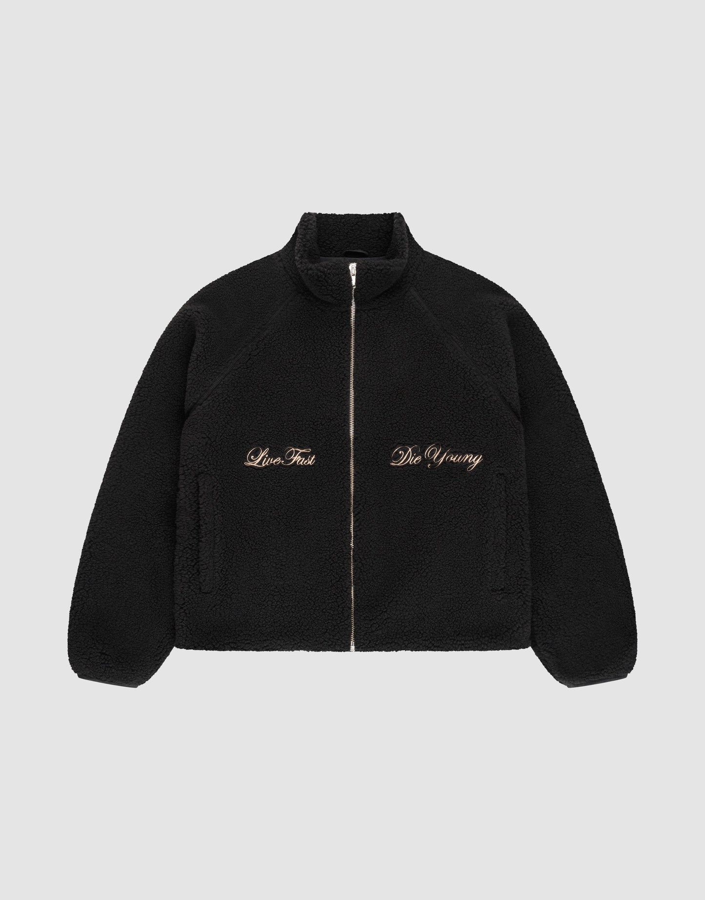 The LFDY Teddy Jacket by LIVE FAST DIE YOUNG is a black fleece jacket with raglan sleeves, side pockets, and gold "Live Fast" and "Die Young" embroidery on the chest, shown on a plain light gray background. | plain