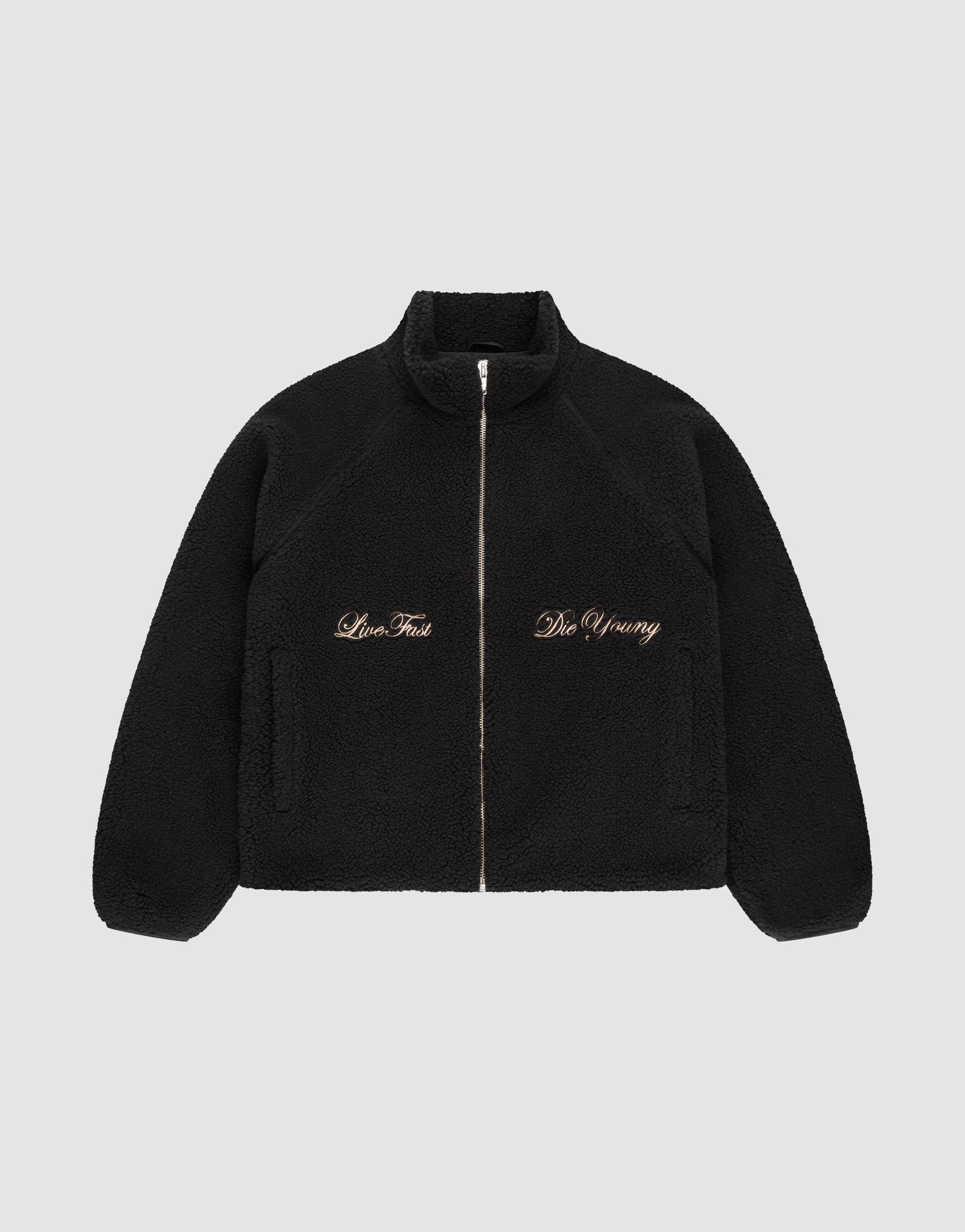The LFDY Teddy Jacket by LIVE FAST DIE YOUNG is a black fleece jacket with raglan sleeves, side pockets, and gold "Live Fast" and "Die Young" embroidery on the chest, shown on a plain light gray background. | plain