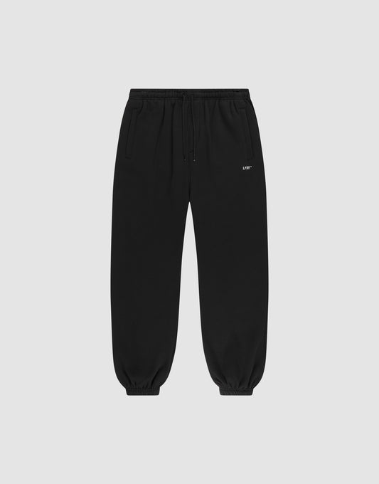 The Basic Loose Jogger by LIVE FAST DIE YOUNG features an elastic waistband and cuffs, side pockets, a drawstring waist, and a small white logo on the left thigh, shown against a light gray background. | plain