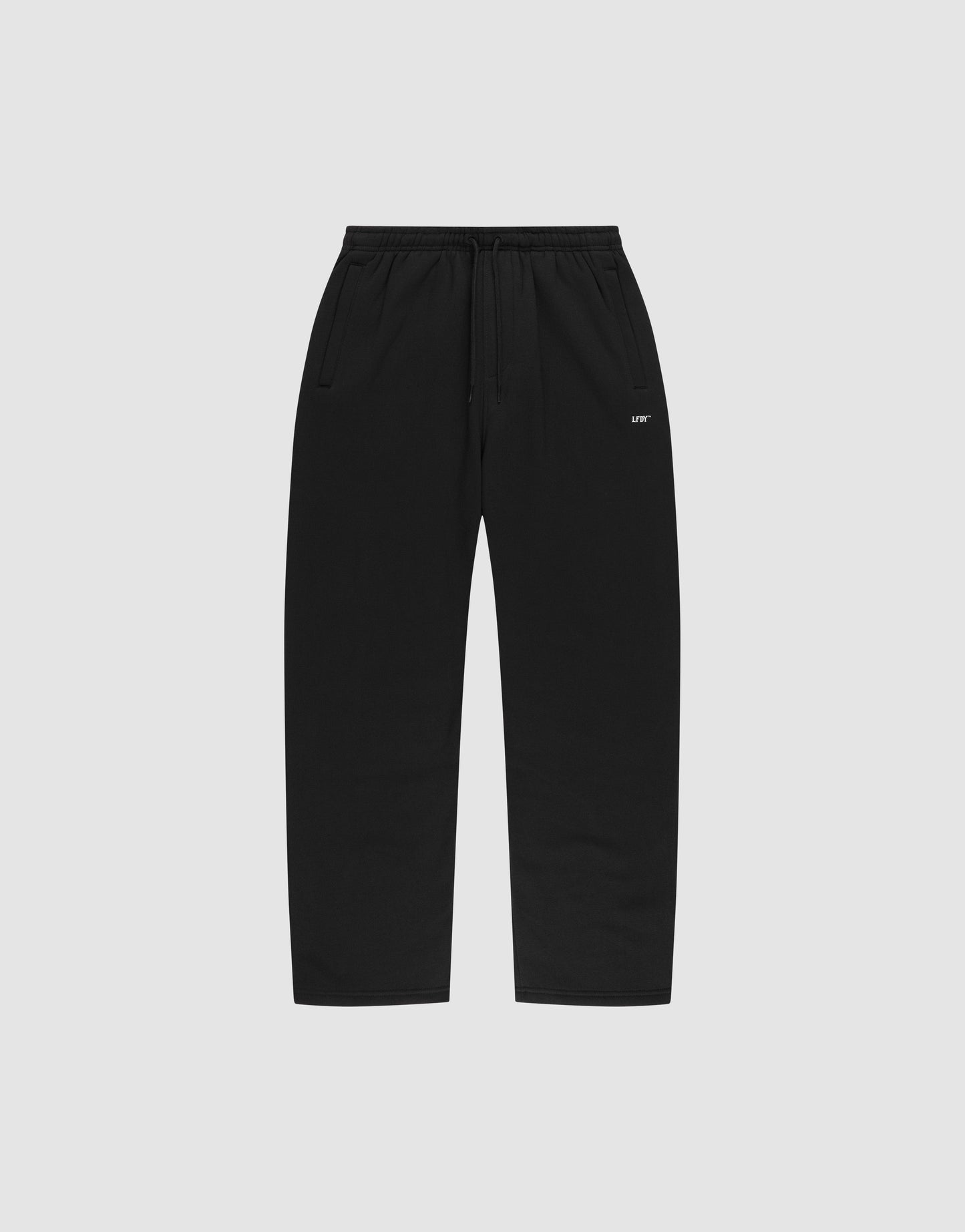 The LIVE FAST DIE YOUNG Basic Wide Jogger features black straight-leg sweatpants with an elastic waistband, drawstring, side pockets, and a small white logo print near the left pocket, shown on a plain light gray background.