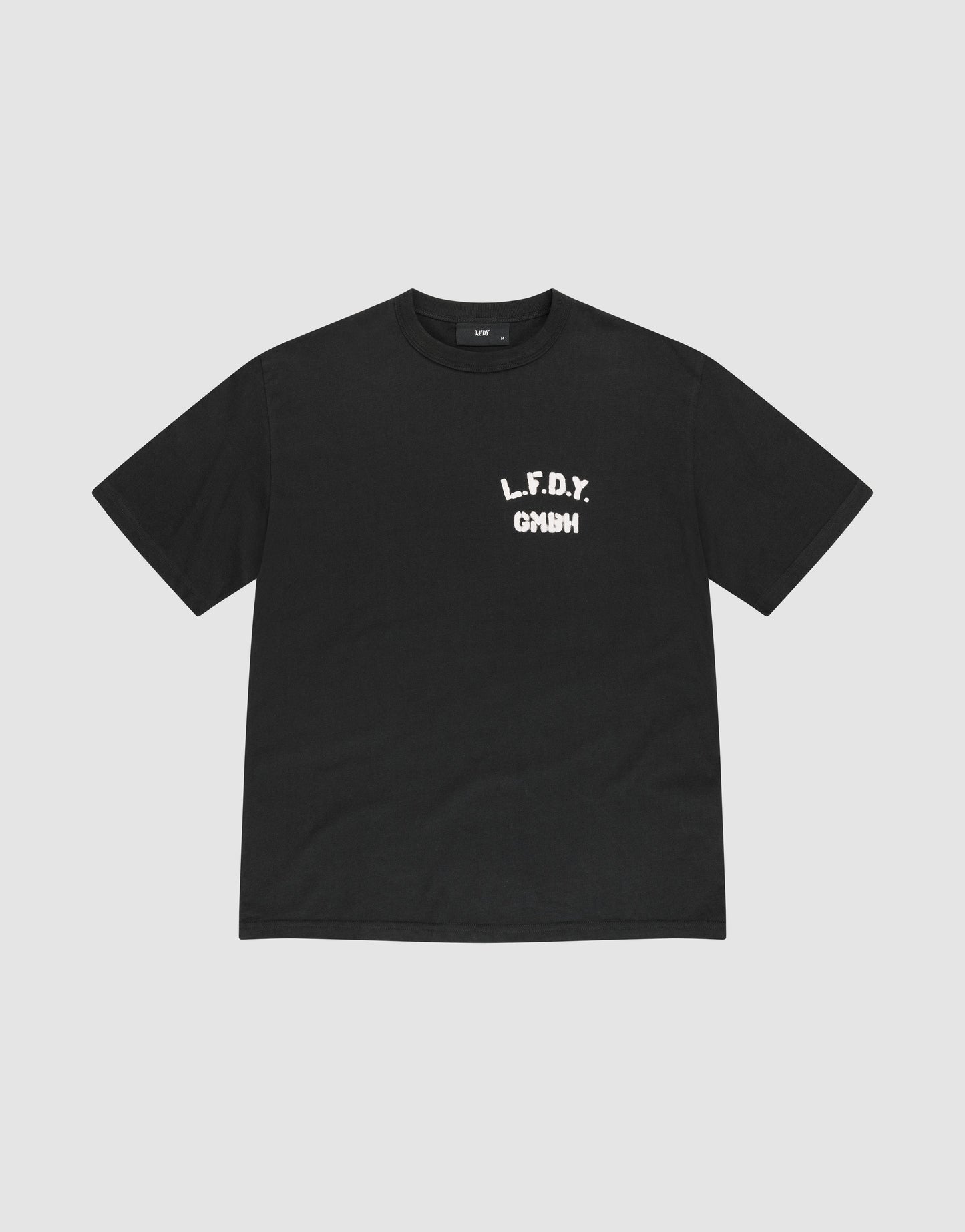 The LFDY District Tee by LIVE FAST DIE YOUNG is a black regular fit short-sleeve t-shirt made from 100% cotton. It features bold white L.F.D.Y. GYM text in a distressed font on the left chest and is shown laid flat on a light gray background. | plain