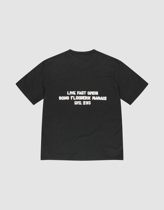 The LFDY District Tee by LIVE FAST DIE YOUNG is a black Regular Fit t-shirt made from 100% cotton, featuring bold front and back prints with white text on the back: "LIVE FAST GMBH SOHO FLOROICK MARAIS INC 235.