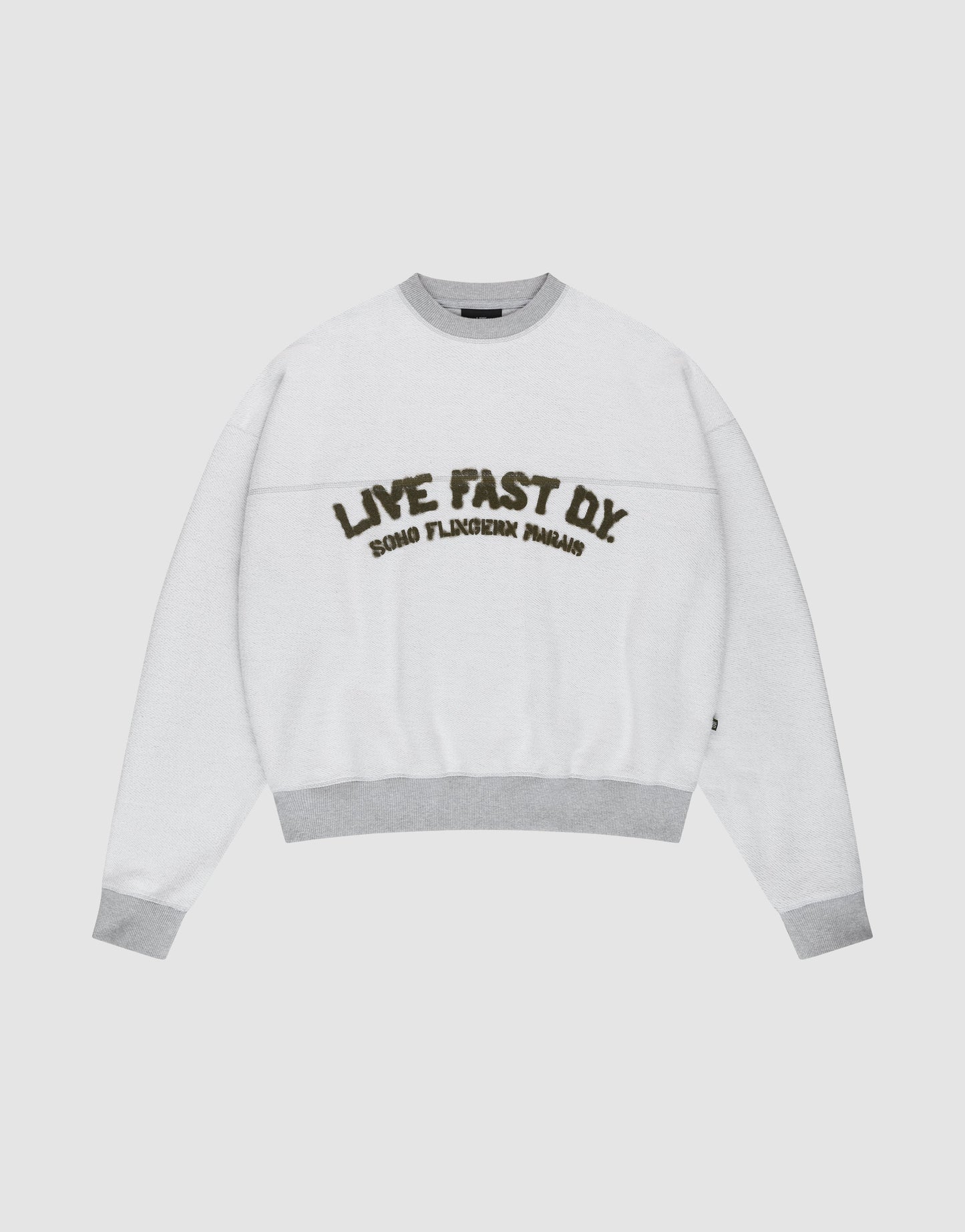 The LFDY District Sweater by LIVE FAST DIE YOUNG is a white oversized crewneck with light gray collar, cuffs, and hem in 480 GSM inside-out fabric. The chest displays bold LIVE FAST D.I.Y. text above ROAD FLECHTERIN PARADIS. | plain