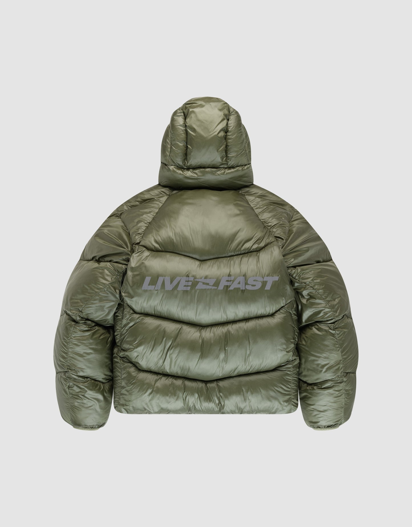 The LIVE FAST DIE YOUNG Live Fast Puffer Jacket in olive green nylon features an oversized fit with hood and “LIVE FAST” reflective back print. Shown from the back against a light gray background.