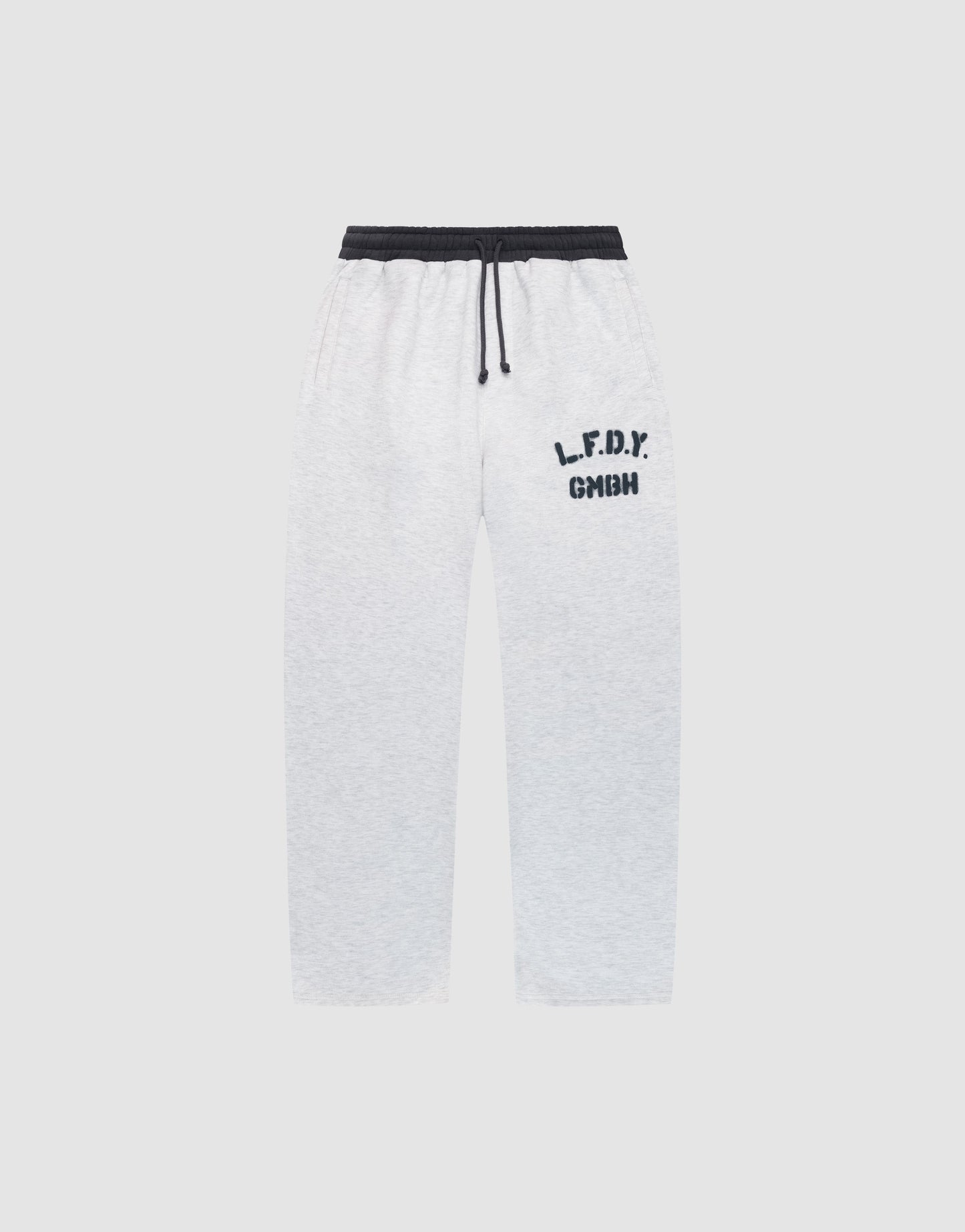 The LFDY District Jogger by LIVE FAST DIE YOUNG features a wide fit in light gray, black elastic waistband with drawstring, black "L.F.D.Y." and "GMHN" prints on the left thigh, plus zip pockets. Displayed on a plain light background.