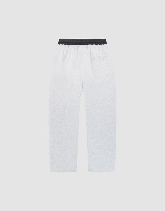 The LFDY District Jogger by LIVE FAST DIE YOUNG, featuring wide-fit white sweatpants with 65% cotton, a black elastic waistband, side pockets, and a back patch pocket, is displayed flat on a plain light gray background.