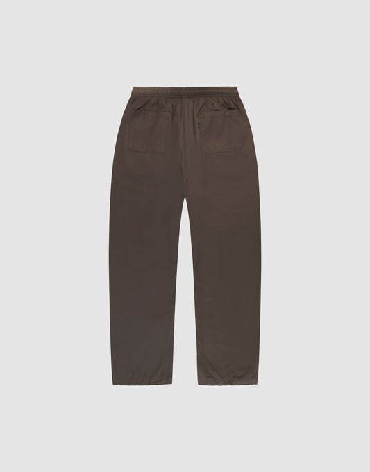 LIVE FAST DIE YOUNG Baggy Nylon Pants in brown wide fit, shown flat from the back on a light gray background, feature an elastikbund, two back pockets (one with button), and practical seitliche Eingrifftaschen.