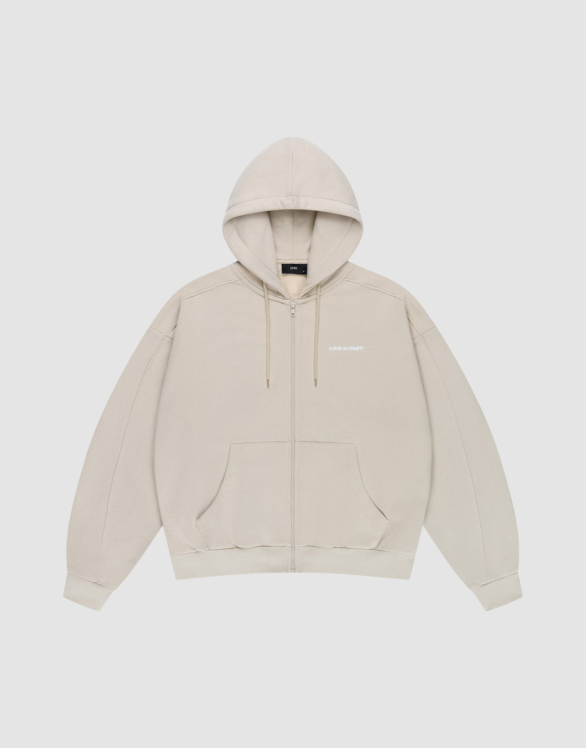 The LFDY Pleated Hooded Zip by LIVE FAST DIE YOUNG is a light beige oversized zip-up hoodie with a drawstring hood, front pockets, and small white logo on the chest. Made from 100% cotton and shown against a plain white background. | plain