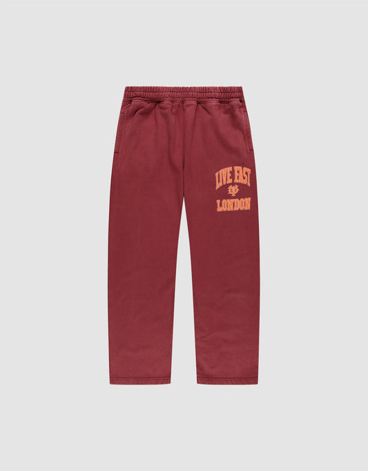 The LIVE FAST DIE YOUNG Live Fast London Wide Jogger in maroon, made from cotton, features a wide elastic waistband, side pockets, and "LIVE FAST LONDON" in yellow on the left thigh. Pants shown laid flat on a light gray background. | plain