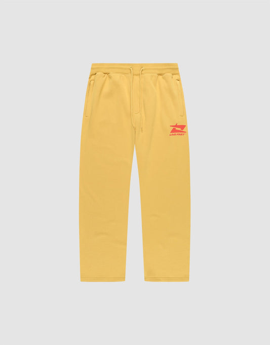 The LIVE FAST DIE YOUNG Live Fast Sweatsuit Jogger features yellow wide-fit sweatpants with side pockets, an elastic drawstring waist, and red LIVE FAST text plus graphic on the left thigh, shown on a plain light grey background. | plain