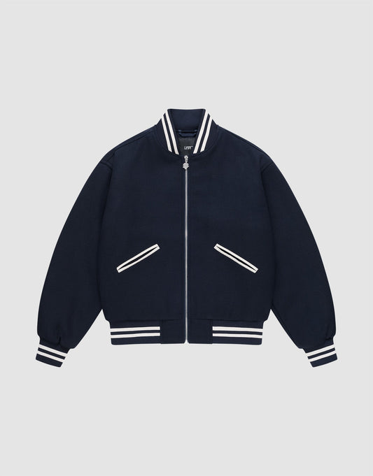 The Live Fast College Jacket by LIVE FAST DIE YOUNG is a navy varsity jacket with white striped ribbed collar, cuffs, and hem, a DY-Reißverschluss front zipper, and two diagonal zippered pockets with white trim on a light gray background.