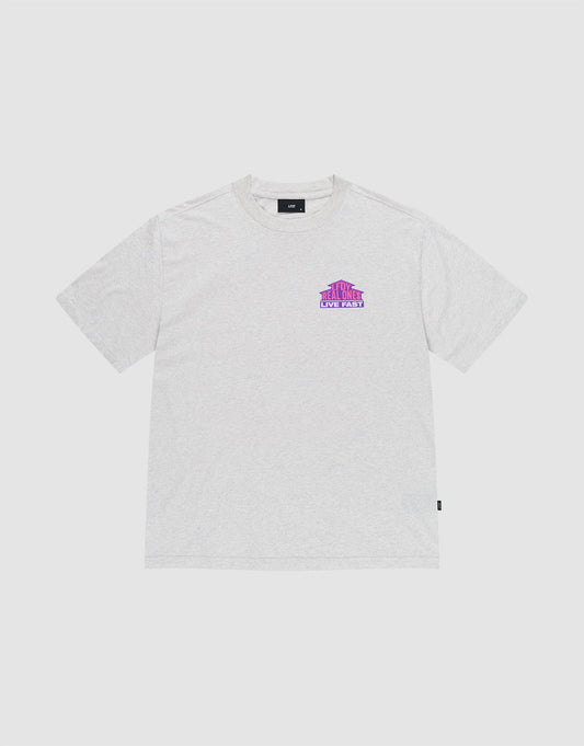 The LFDY Real Ones Tee by LIVE FAST DIE YOUNG is a light gray, oversized short-sleeve t-shirt featuring a small purple and pink THE TRAVELER NEW WAVE graphic on the left chest and a subtle Flaglabel, shown on a white background.