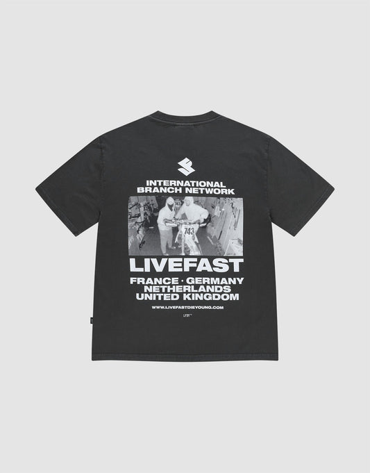 The LFDY Grand Theft Tee by LIVE FAST DIE YOUNG is an oversized black T-shirt made from 100% cotton, featuring bold front and back prints of runners, “INTERNATIONAL BRANCH NETWORK,” “LIVEFAST,” and country names. | plain