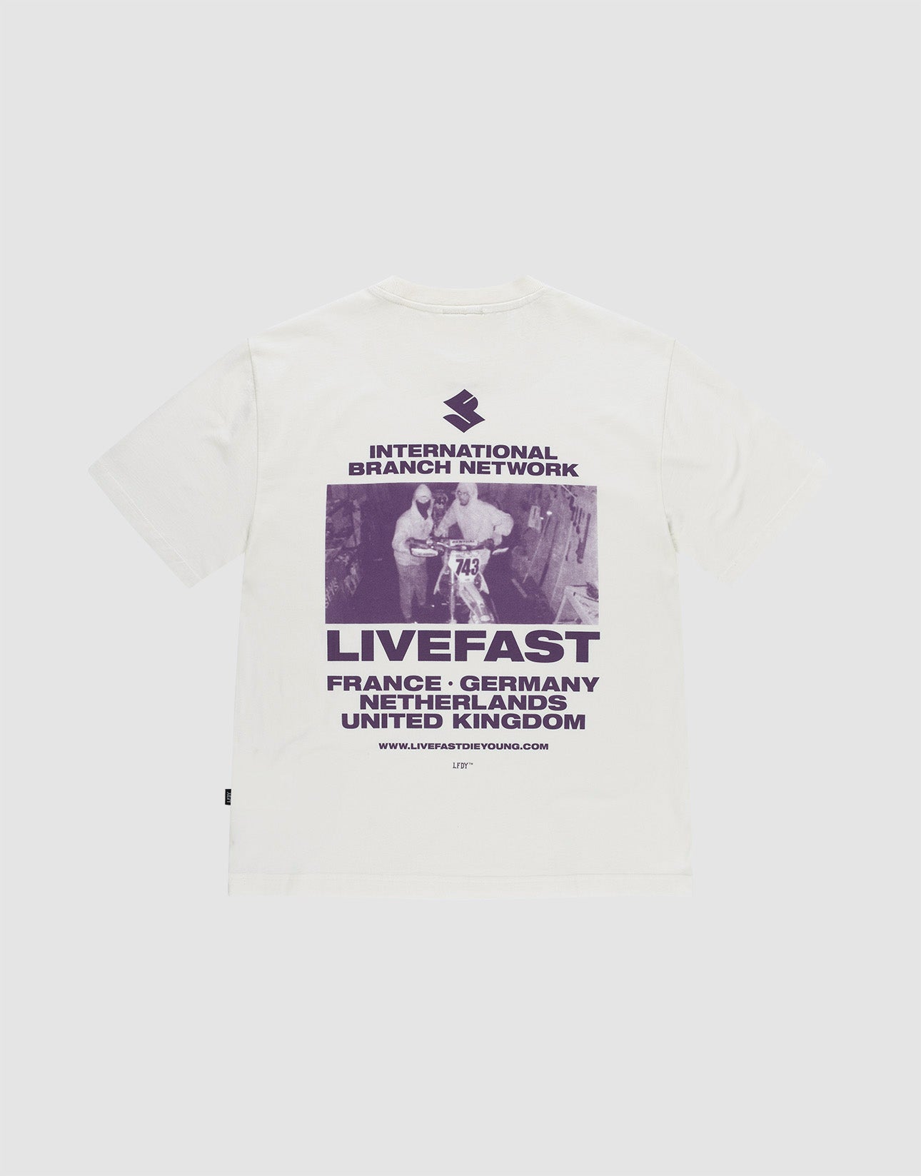 Das LFDY Grand Theft Tee von LIVE FAST DIE YOUNG ist ein weißes Oversize-Shirt aus 100% Baumwolle mit lila Backprint eines Skateboarders und Prints mit "INTERNATIONAL BRANCH NETWORK, LIVEFAST" sowie Ländernamen wie France und Germany. | plain