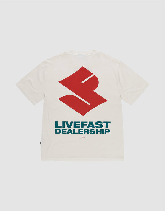 The LFDY Dealership Tee by LIVE FAST DIE YOUNG is an oversized white 100% cotton t-shirt, featuring a large red geometric backprint above bold blue "LIVEFAST DEALERSHIP" text and a small "LFTF" below, shown on a plain background. | plain