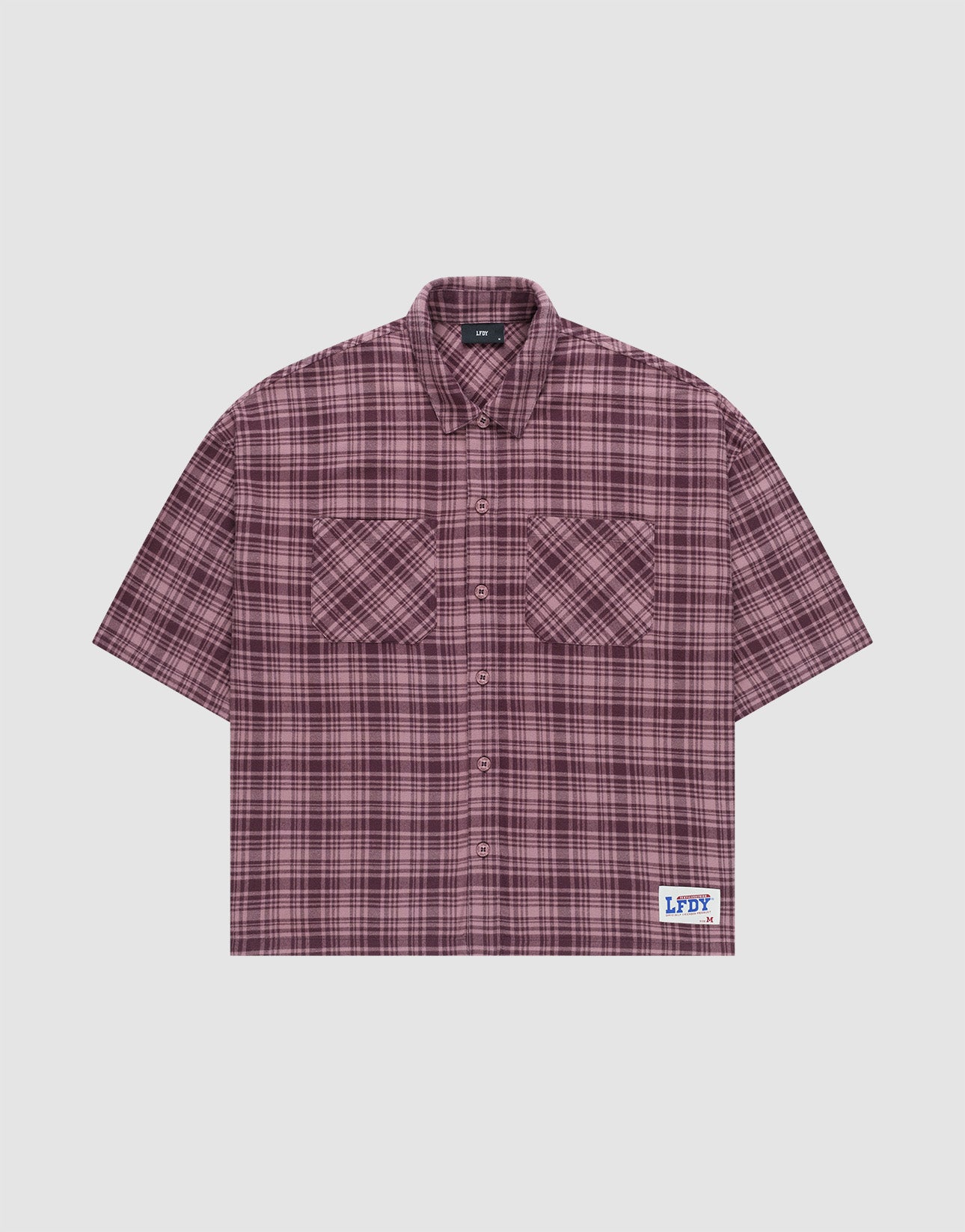The LFDY Light Flannel by LIVE FAST DIE YOUNG is a maroon and black plaid, short-sleeve, button-up oversize fit shirt with two chest pockets and a white patch featuring blue branding near the hem. Made from 100% cotton. Laid flat on a plain background.