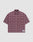 The LFDY Light Flannel by LIVE FAST DIE YOUNG is a maroon and black plaid, short-sleeve, button-up oversize fit shirt with two chest pockets and a white patch featuring blue branding near the hem. Made from 100% cotton. Laid flat on a plain background.