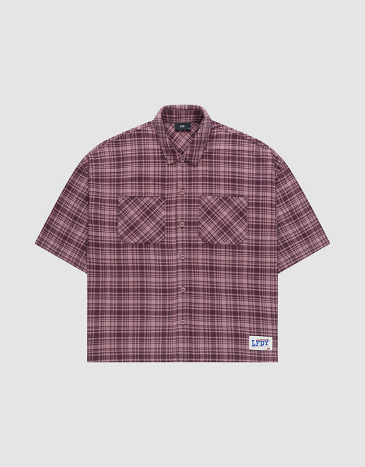 The LFDY Light Flannel by LIVE FAST DIE YOUNG is a maroon and black plaid, short-sleeve, button-up oversize fit shirt with two chest pockets and a white patch featuring blue branding near the hem. Made from 100% cotton. Laid flat on a plain background. | plain