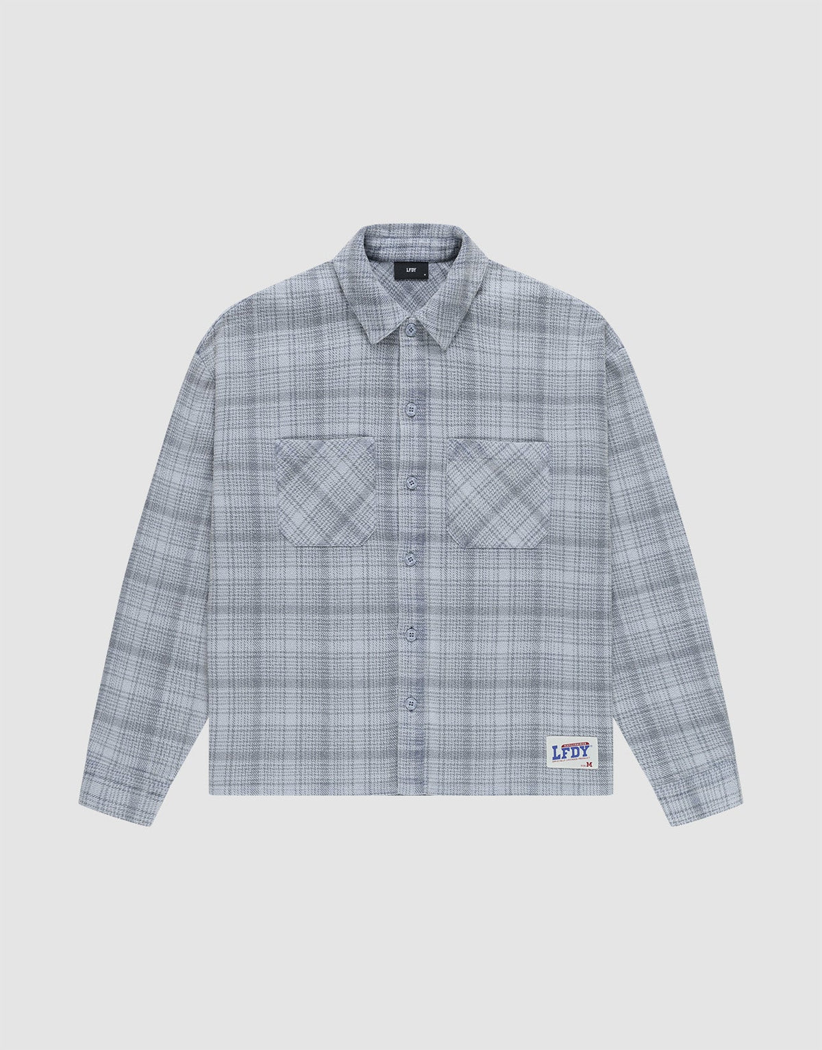 The Vintage Flannel by LIVE FAST DIE YOUNG is a gray plaid, long-sleeve, button-up shirt with two chest pockets and a small LFDY patch near the hem, featuring an oversize fit and vintage wash, shown laid flat on a white background. | plain