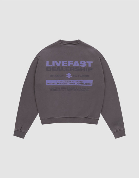 The LFDY Network Sweater von LIVE FAST DIE YOUNG ist ein graues Oversize-Crewneck aus Baumwolle mit lila "LIVEFAST DEALERSHIP" Backprint, weiteren Details, Website und Kleingedrucktem. Flach auf weißem Hintergrund präsentiert. | plain
