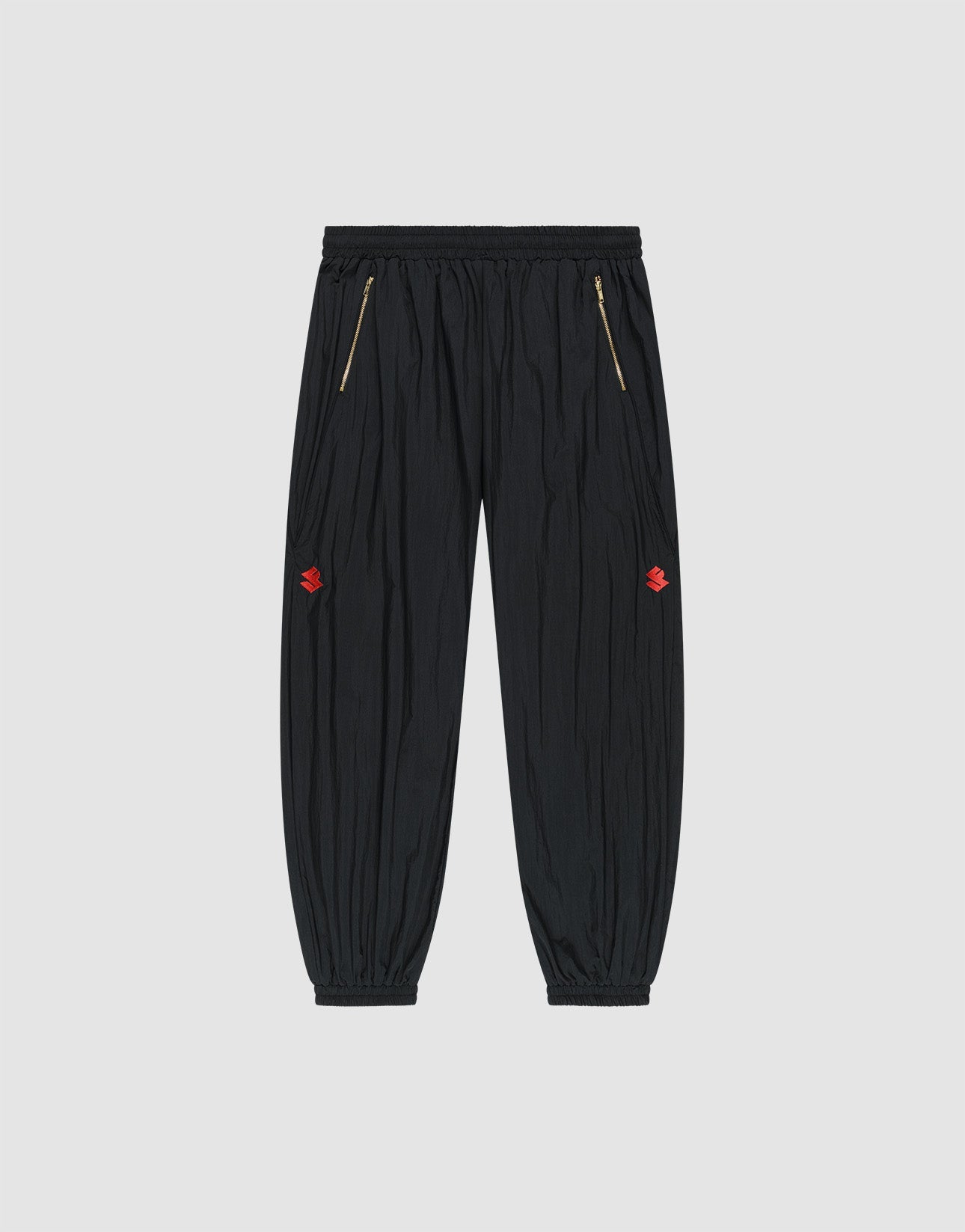 The LFDY Dealership Trackpants by LIVE FAST DIE YOUNG feature an elastic waistband, gold zippered side pockets, ankle cuffs, and small red embroidered thigh logos. Made from comfortable polyamide. Shown against a light gray background. | plain