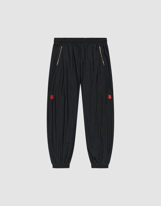The LFDY Dealership Trackpants by LIVE FAST DIE YOUNG feature an elastic waistband, gold zippered side pockets, ankle cuffs, and small red embroidered thigh logos. Made from comfortable polyamide. Shown against a light gray background. | plain