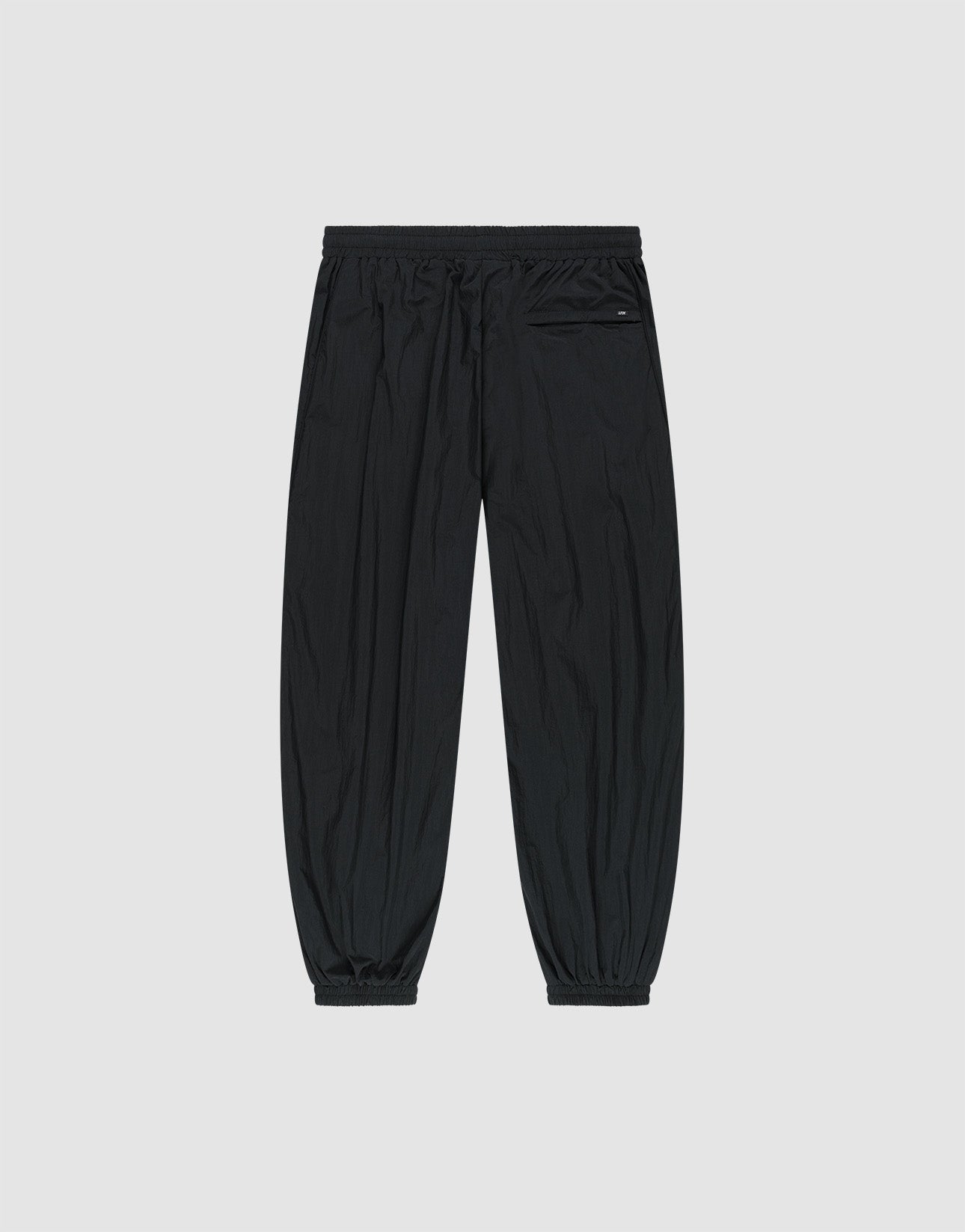The LFDY Dealership Trackpants by LIVE FAST DIE YOUNG feature a black wide fit, polyamide material, elastic waistband and cuffs, and a left zip pocket. Shown laid flat on a light gray background.