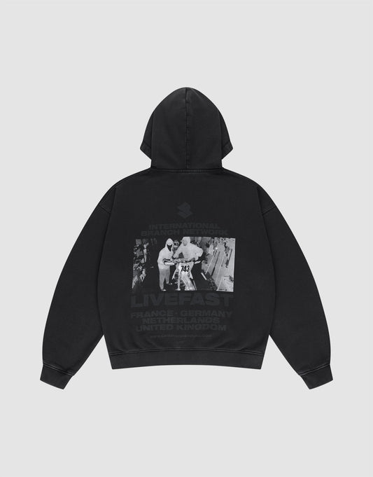 Die LFDY Grand Theft Hooded Zip von LIVE FAST DIE YOUNG ist ein Oversize-Hoodie aus Baumwolle mit Kapuze. Auf dem Rücken: Schwarz-Weiß-Foto mit zwei Personen, Graffiti und den Schriftzügen INTERNATIONAL BRAND, LIVE FAST und Ländernamen. | plain