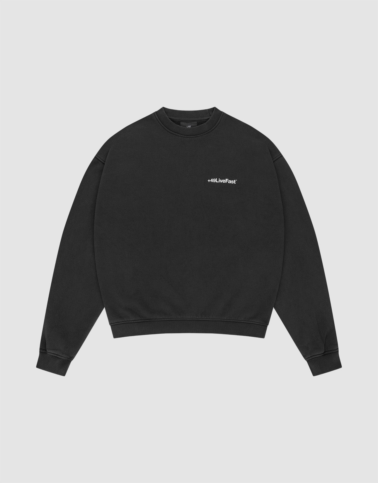The LIVE FAST DIE YOUNG Basic +49 Chest Sweater is a black, oversized crewneck with ribbed cuffs and a small white #LLJLiveFast chest print, made from a cotton-polyester blend, shown flat on a light gray background. | plain