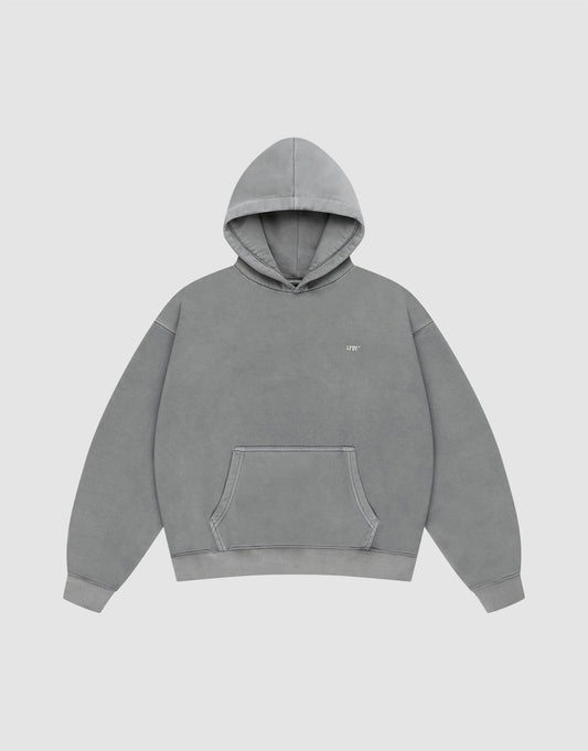 The LIVE FAST DIE YOUNG Basic Evidence Hooded is a plain gray oversized hoodie with a front pocket, hood, and small white text on the left chest. It’s styled against a plain white background.