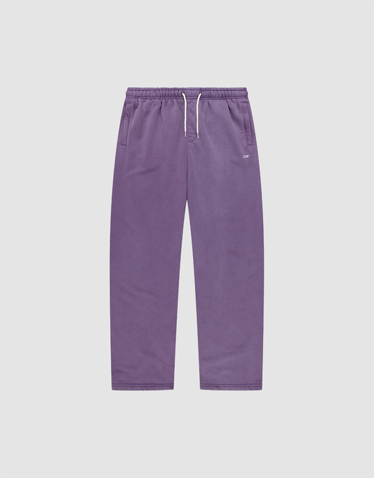 The Basic Wide Jogger by LIVE FAST DIE YOUNG features a purple color, elastic waistband, white drawstring, side pockets, and a relaxed wide fit. Shown laid flat on a plain light grey background. | plain