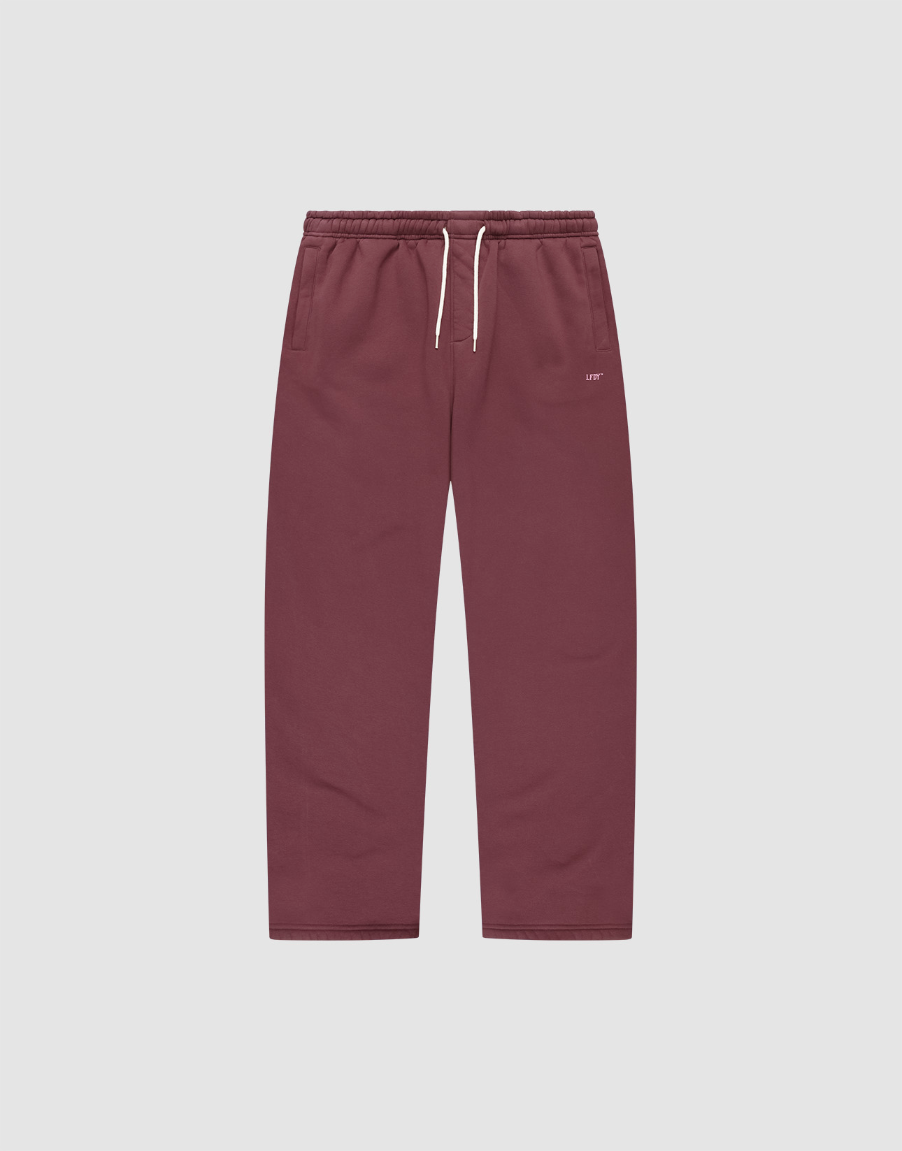 The Basic Wide Jogger by LIVE FAST DIE YOUNG features a burgundy color, elastic waistband, white drawstring, side pockets, and a small white LIVI logo-print on the left hip. The wide fit pants are shown laid flat on a light background. | plain