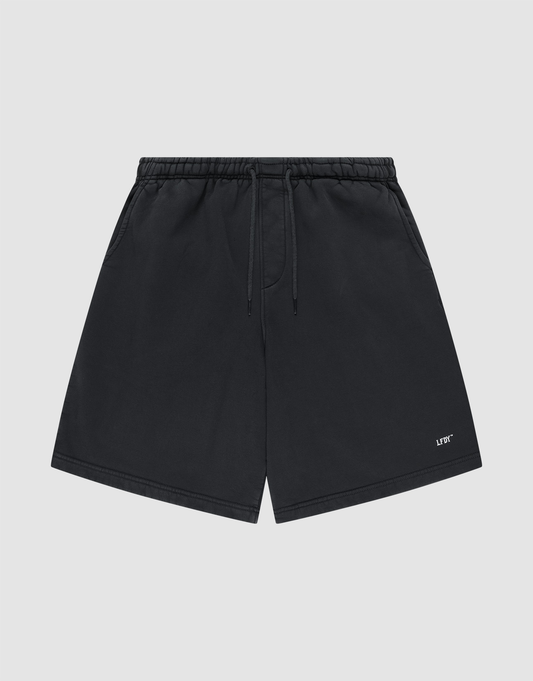 Basic Shorts by LIVE FAST DIE YOUNG in black, featuring an elastic waistband, side pockets, and a small white logo print on the lower left leg, shown against a plain light gray background. | plain