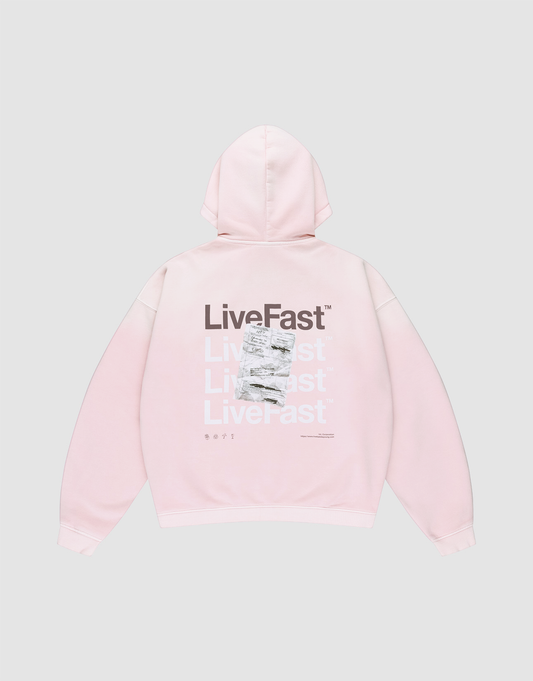 The Basic Evidence Hooded Zip by LIVE FAST DIE YOUNG is a light pink oversized hoodie with “LiveFast” in white and gray on the back, black “LiveFast” at the top, LFDY branding, and a crumpled graphic layered over part of the text. | plain