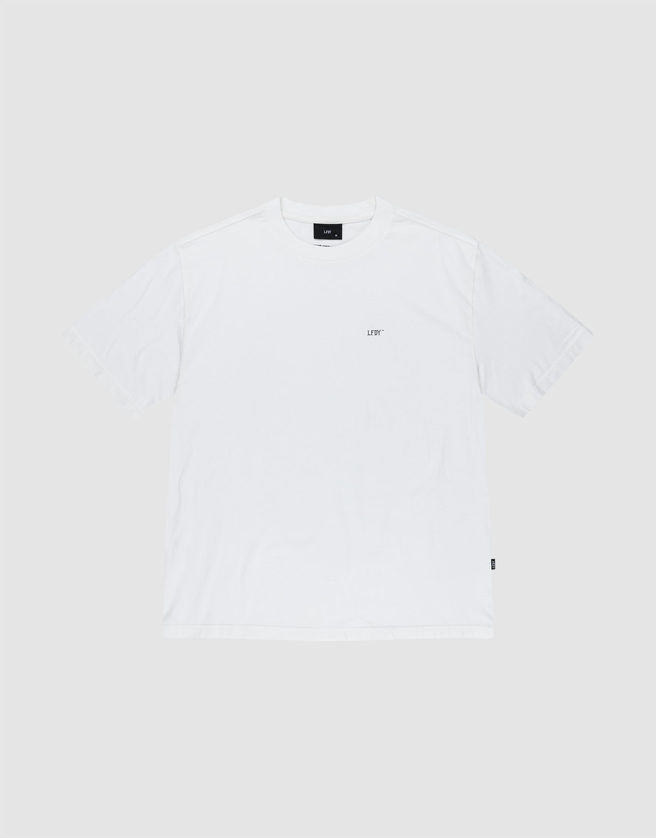 The LFDY Zizou Tee by LIVE FAST DIE YOUNG is a plain white short-sleeve crew neck T-shirt made from 100% Baumwolle. It features a small LIV* print on the left chest, a black rectangular tag at the neckline, minimal design, and a relaxed fit.